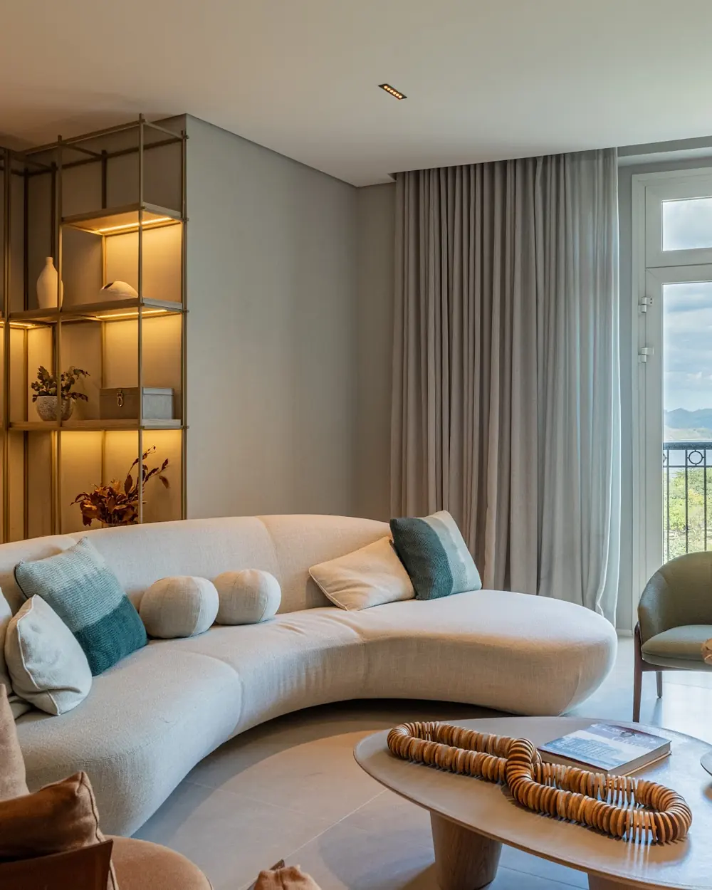 Sala decorada de apartamento do Glória Residencial, com sofá curvo e janelas para o Parque do Flamengo